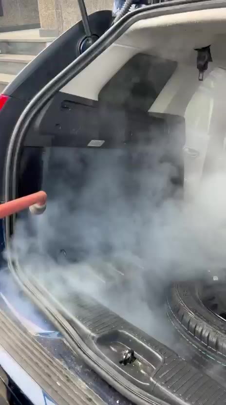 Technicien Steam Car passant la vapeur dans le coffre d’une Dacia Logan MCV